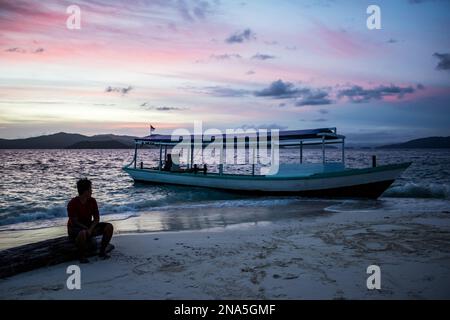 Bateau sur la plage au coucher du soleil, Pulau Kelelawar (île de Bat) ; Papouasie occidentale, Indonésie Banque D'Images