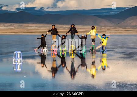 Touristes posant dans le reflet pendant la saison humide (décembre-février) dans le Salar de Uyuni, la plus grande plate-forme saline du monde Banque D'Images