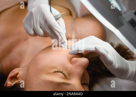 Esthéticienne en gants travail sur le visage de la femme client avec la seringue gros plan, électrolyse visage enlèvement de cheveux, procédures de beauté Banque D'Images