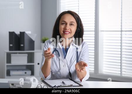 Médecin avec micro-casque à la table au bureau. Service d'assistance téléphonique Banque D'Images