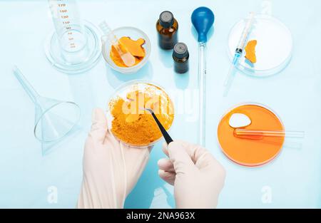 Recherche médicale sur les propriétés de curcuma avec l'aide d'équipements de laboratoire, femme en gants testant la poudre curcuma. Vue de dessus. Banque D'Images