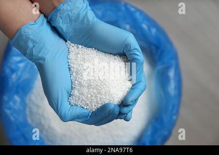 Personne en gants tenant une pile de granulés de nitrate d'ammonium au-dessus du sac, vue du dessus. Engrais minéral Banque D'Images