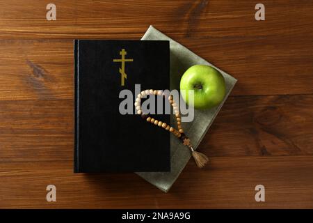 Bible, perles rosaires et pomme sur table en bois, plat. Saison prêtée Banque D'Images