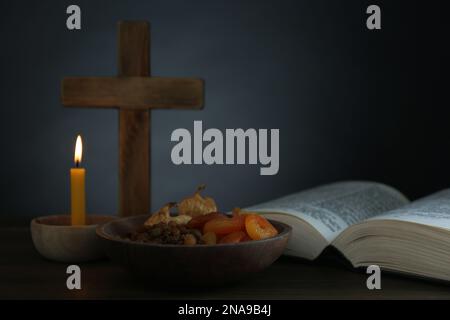 Croix, Bible, bougie et fruits secs sur table en bois, espace pour le texte. Saison prêtée Banque D'Images