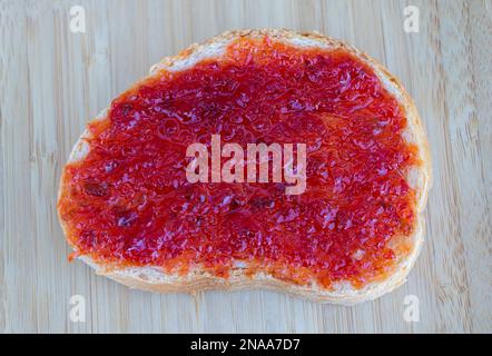 Plats rustiques : confiture de poivre sur des toasts avec fond en bois. Banque D'Images