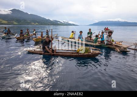 Des insulaires en canoës-outrigger vendent des fruits tropicaux au large de Dobu dans les îles d'Entrecasteaux, Papouasie-Nouvelle-Guinée Banque D'Images