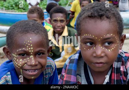 Garçons avec de la peinture faciale sur la rive du village de Siboma, île de Lababia, golfe de Huon, province de Morobe, Papouasie-Nouvelle-Guinée Banque D'Images