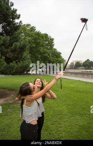 Au Parc de la Villette, deux filles utilisent un poteau pour prendre un autoportrait à Paris, France ; Paris, France Banque D'Images