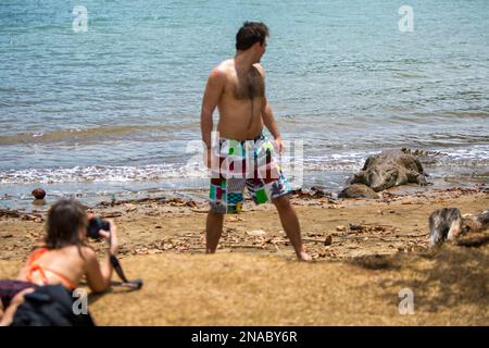 Dans le parc national de Coiba, une femme photographie un homme qui observe attentivement un crocodile américain voisin (Crocodylus acutus) sur les îles Coiba au Panama Banque D'Images