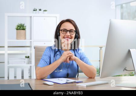 Médecin avec micro-casque à la table au bureau. Service d'assistance téléphonique Banque D'Images