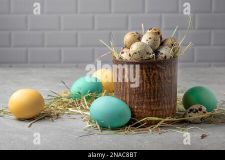 Vaisseau en argile avec oeufs de caille dans le foin entouré d'oeufs de poulet peints Banque D'Images