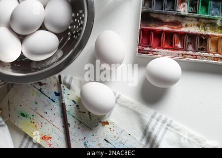 Peinture des oeufs de Pâques sur une table blanche, ponte plate Banque D'Images