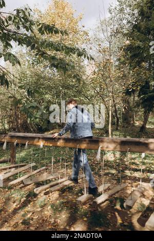 l'homme marche sur un pont suspendu en bois dans le parc Banque D'Images