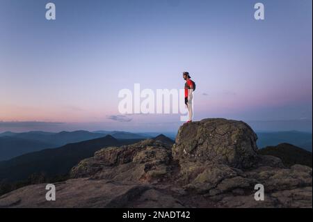 Coureur de sentier, homme debout sur le rocher au sommet de la montagne au lever du soleil Banque D'Images