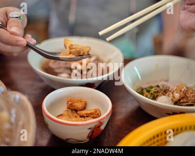 Nouilles de bateau thaïlandaises dans la soupe épaissie, ajout de sang avec des boules de porc, émincé de bœuf et de foie et peau de porc frite croustillante. Banque D'Images