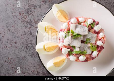 Portion de salade de légumes scandinave avec hareng, betterave, pomme, pomme de terre et oignon dans une assiette sur la table. Vue horizontale du dessus de abo Banque D'Images