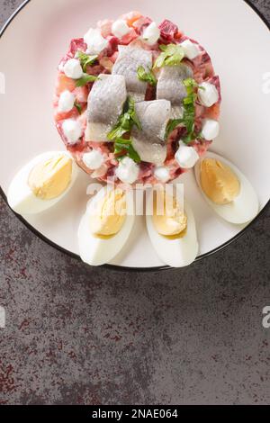 Sillsallad Herring salade avec des légumes vêtus de crème aigre et décoré avec des œufs durs dans une assiette sur la table. vue verticale du dessus fr Banque D'Images