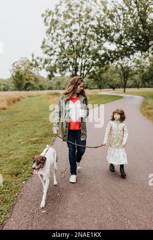 Une mère et des filles marchent le chien de leur famille le long du chemin de marche Banque D'Images