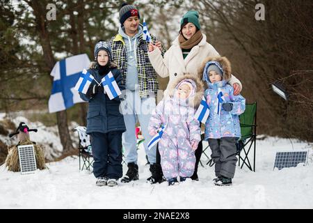 Famille finlandaise avec drapeaux finlandais lors d'une belle journée d'hiver. Nordic Scandinaves. Banque D'Images