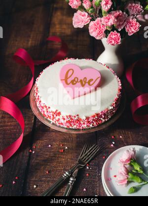 Gâteau de la Saint-Valentin avec cœur saupoudrer et fleurs sur une table en bois. Banque D'Images