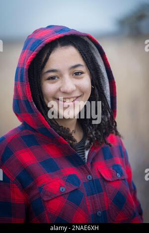 portrait de la jeune femme biraciale souriant avec des tresses et une cagoule Banque D'Images