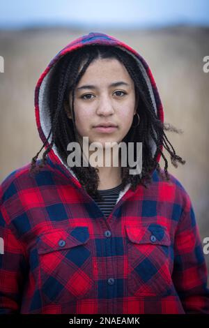 portrait d'une jeune femme biraciale avec une expression sérieuse portant une capuche Banque D'Images