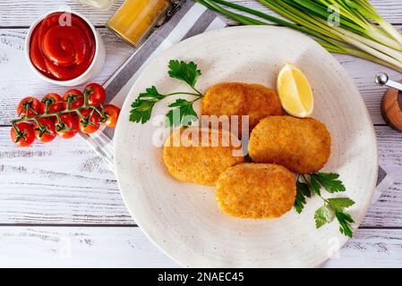 côtelettes de poulet dans une assiette sur fond en bois clair Banque D'Images
