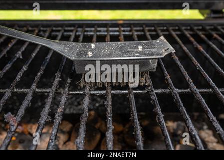 Nettoyer un gril sale en se tenant sur la terrasse et en vidant les cendres. Banque D'Images