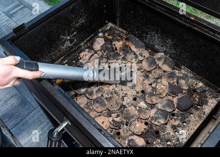 Nettoyer un gril sale en se tenant sur la terrasse et en vidant les cendres. Banque D'Images