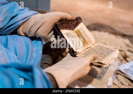 Livres anciens Qur'anic présentés par le bibliothécaire portant des gants Banque D'Images