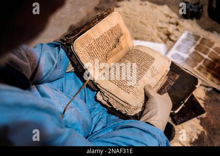 Livres anciens Qur'anic présentés par le bibliothécaire portant des gants Banque D'Images