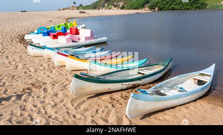 Destination estivale pittoresque de vacances à la plage rivière lagon estuaire avec bateaux à aubes canoës kayaks de différentes couleurs et formes sur la ligne d'eau de sable à proximité Banque D'Images