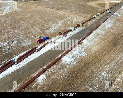 Vue aérienne de la construction d'un pipeline dans un champ enneigé, à l'ouest de Calgary; Alberta, Canada Banque D'Images