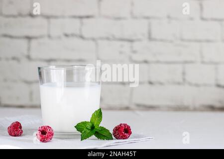 Boisson au kéfir au lait biologique probiotique ou yaourt dans des récipients en verre, avec framboise, sur fond gris blanc. Santé intestinale. Probiotique fermenté à froid d Banque D'Images