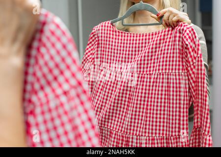 une femme prend une robe rouge hors du placard. femme essayant une robe d'été. robe d'été. femme portant une nouvelle robe Banque D'Images