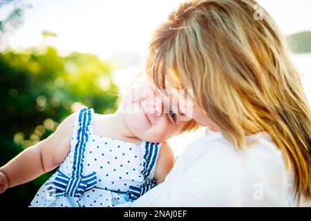 Une petite fille s'est cachée dans la poitrine de sa mère. Fille timide. Le gamin dans les bras de sa mère sur la côte. Banque D'Images