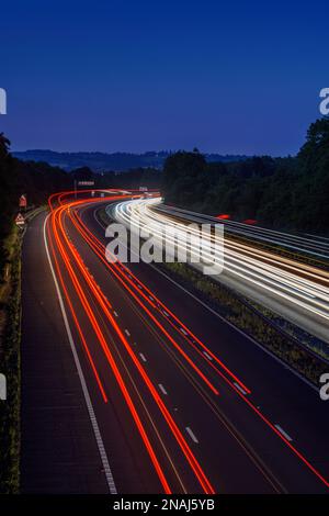 Les voitures qui se déplacent rapidement sur l'autoroute M5 laissent des sentiers de signalisation et des traînées de lumière lorsqu'elles passent le long d'une autoroute très fréquentée Banque D'Images