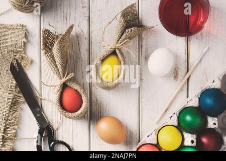 Préparations de Pâques et teintures pour oeufs. Œufs de pâques colorés et œufs de lapin sur fond de bois. Directement au-dessus du plan d'examen. Banque D'Images