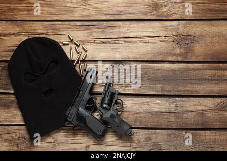 Balaclava, pistolets et balles sur table en bois, plat. Espace pour le texte Banque D'Images