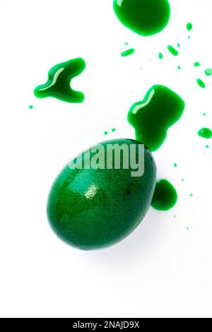 Œuf de pâques vert et colorant alimentaire liquide sur fond blanc. Gros plan. Banque D'Images