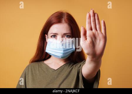 jeune femme portant un masque médical faisant un geste d'arrêt avec sa main - pas d'entrée sans masque pendant corona covid-19 concept de pandémie Banque D'Images