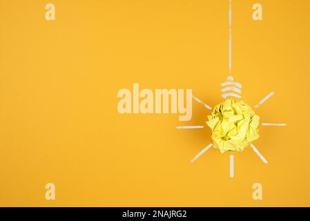 ampoule en papier jaune froissé sur fond orange, concept d'idée et d'innovation Banque D'Images