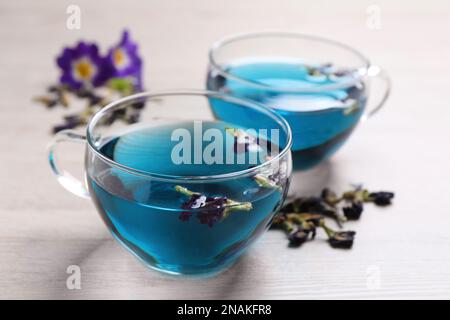 Tasses en verre de bleu biologique Anchan sur table en bois blanc, gros plan. Tisane Banque D'Images