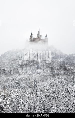 Une image verticale du château Hohenzollern en hiver avec neige et brouillard au-dessus de la forêt. Banque D'Images