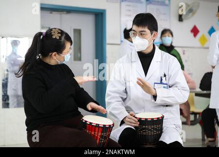 HUAI'AN, CHINE - 13 FÉVRIER 2023 - Un physiothérapeute de musique enseigne à un malade mental de jouer un tambour africain à Huai 'an, province de Jiangsu, Chi Banque D'Images