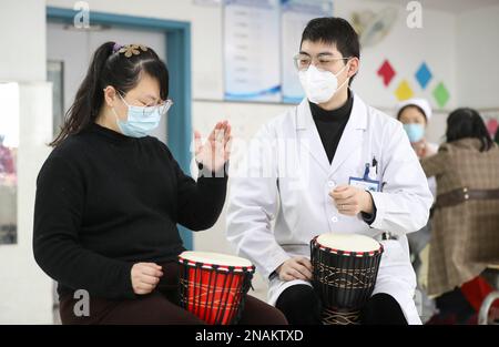 HUAI'AN, CHINE - 13 FÉVRIER 2023 - Un physiothérapeute de musique enseigne à un malade mental de jouer un tambour africain à Huai 'an, province de Jiangsu, Chi Banque D'Images
