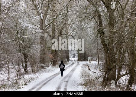 Route de terre enneigée et isolée avec piéton en hiver avec neige et glace à Hesse, en Allemagne Banque D'Images