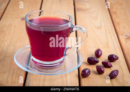 Un verre de thé aux hanches roses et de graines de rosehip sur une table en bois Banque D'Images