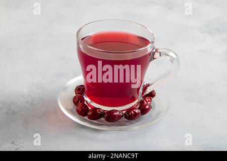 Un verre de thé aux hanches roses et de graines de rosehip sur fond bleu vif Banque D'Images