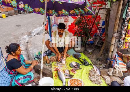 Détenteur local de la rue coupant, trancher et préparer le poisson à vendre dans un stalle situé sur le bord de la route à Fariapukur, Shyam Bazar, Kolkata, Bengale occidental, Inde Banque D'Images